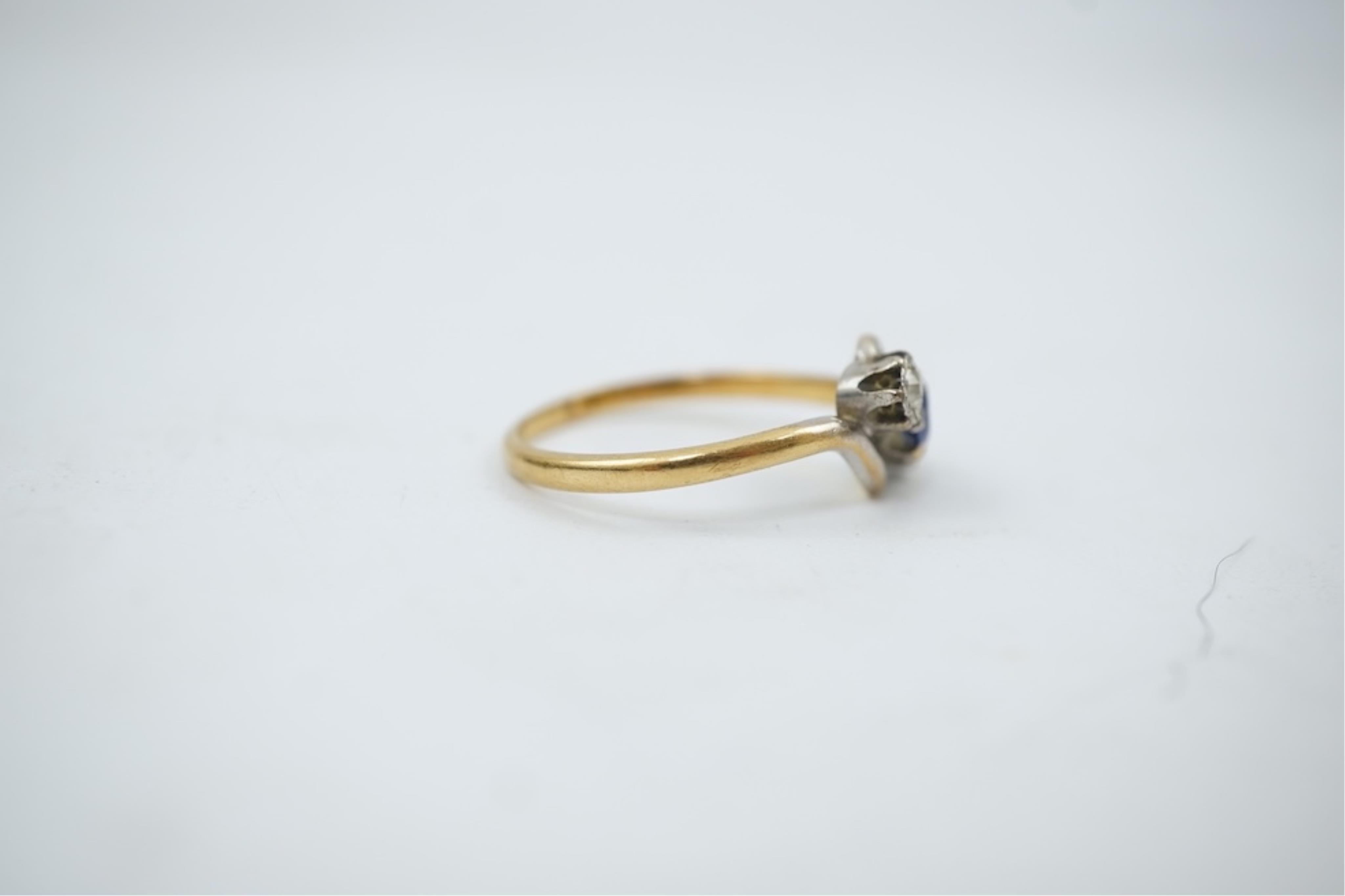 An early 20th century 18ct gold, sapphire and diamond set three stone crossover ring, size P/Q, gross weight 2.4 grams.
